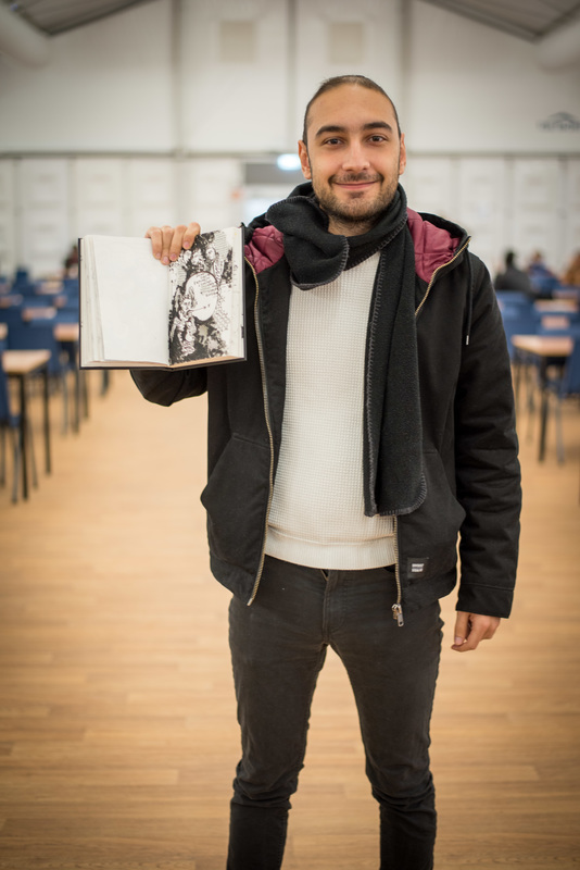 Illustrator Fadi Nadrous toont een van zijn illustraties in een boek.